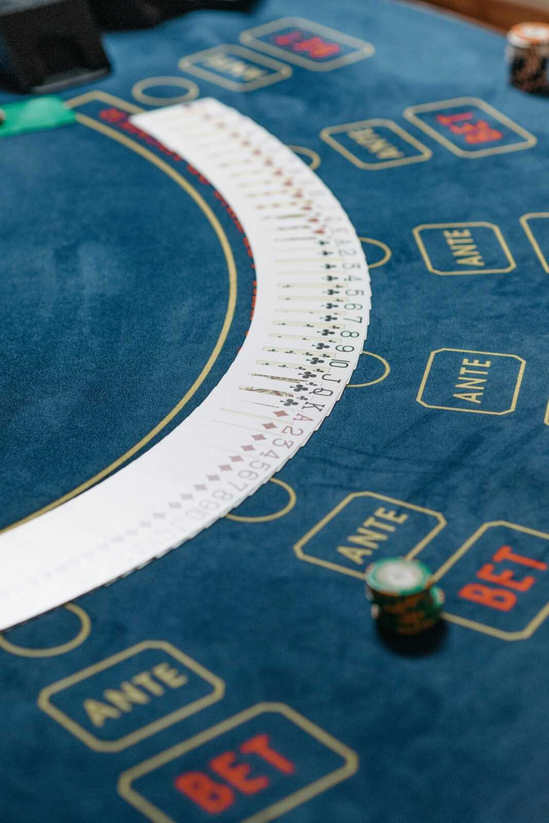 Close-up of a casino table featuring playing cards fanned out and poker chips for gambling.